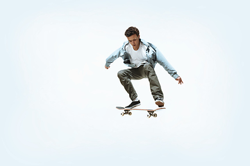 Image showing Caucasian young skateboarder riding isolated on a white background