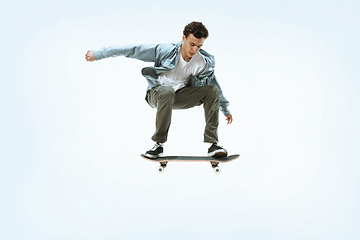 Image showing Caucasian young skateboarder riding isolated on a white background