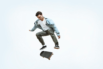 Image showing Caucasian young skateboarder riding isolated on a white background