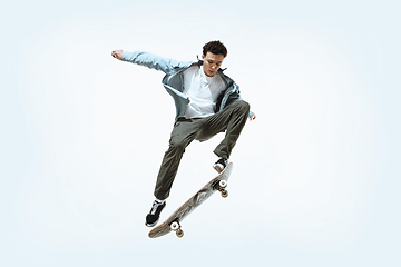 Image showing Caucasian young skateboarder riding isolated on a white background