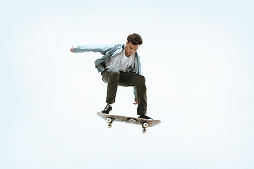 Image showing Caucasian young skateboarder riding isolated on a white background