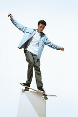 Image showing Caucasian young skateboarder riding isolated on a white background