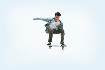 Image showing Caucasian young skateboarder riding isolated on a white background