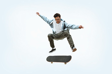 Image showing Caucasian young skateboarder riding isolated on a white background