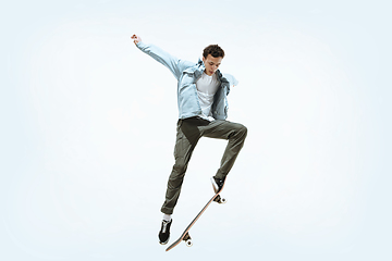 Image showing Caucasian young skateboarder riding isolated on a white background