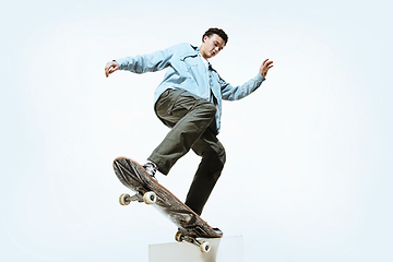 Image showing Caucasian young skateboarder riding isolated on a white background