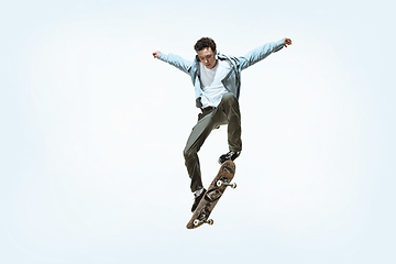 Image showing Caucasian young skateboarder riding isolated on a white background