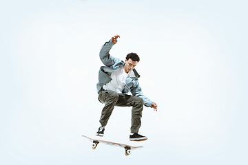 Image showing Caucasian young skateboarder riding isolated on a white background