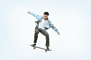 Image showing Caucasian young skateboarder riding isolated on a white background