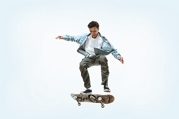 Image showing Caucasian young skateboarder riding isolated on a white background