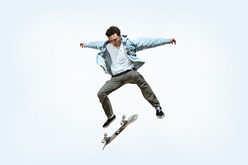 Image showing Caucasian young skateboarder riding isolated on a white background