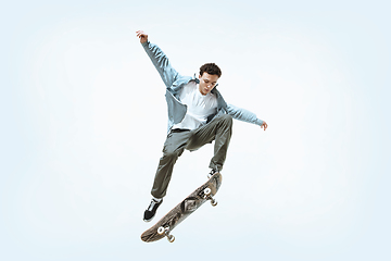 Image showing Caucasian young skateboarder riding isolated on a white background