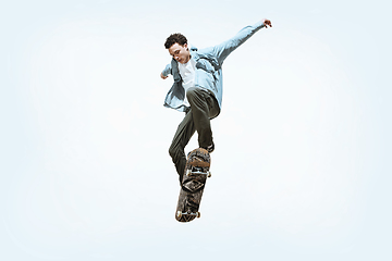 Image showing Caucasian young skateboarder riding isolated on a white background