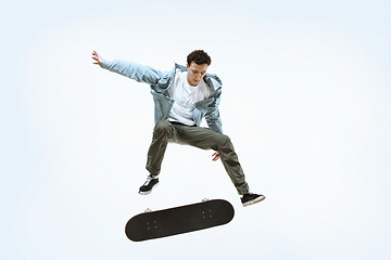 Image showing Caucasian young skateboarder riding isolated on a white background