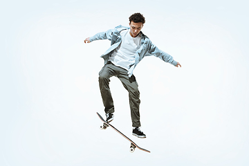 Image showing Caucasian young skateboarder riding isolated on a white background