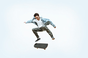 Image showing Caucasian young skateboarder riding isolated on a white background