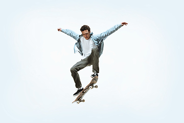 Image showing Caucasian young skateboarder riding isolated on a white background
