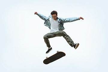 Image showing Caucasian young skateboarder riding isolated on a white background