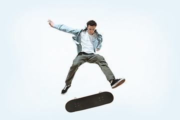 Image showing Caucasian young skateboarder riding isolated on a white background