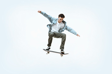 Image showing Caucasian young skateboarder riding isolated on a white background