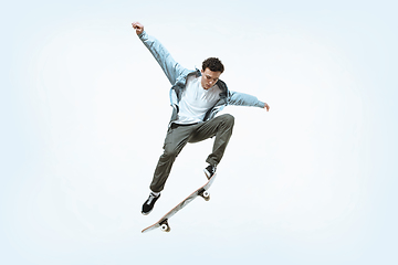 Image showing Caucasian young skateboarder riding isolated on a white background