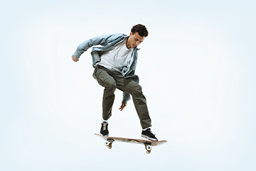 Image showing Caucasian young skateboarder riding isolated on a white background