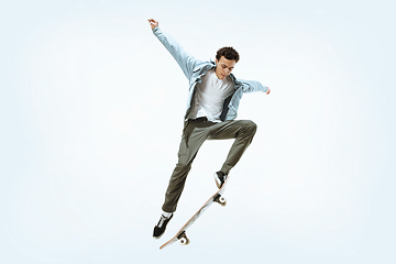 Image showing Caucasian young skateboarder riding isolated on a white background