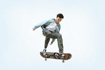 Image showing Caucasian young skateboarder riding isolated on a white background