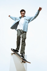 Image showing Caucasian young skateboarder riding isolated on a white background