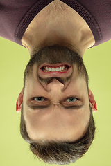 Image showing Inverted portrait of caucasian young man on yellow studio background