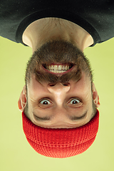 Image showing Inverted portrait of caucasian young man on yellow studio background