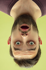 Image showing Inverted portrait of caucasian young man on yellow studio background