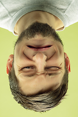 Image showing Inverted portrait of caucasian young man on yellow studio background