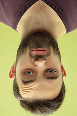 Image showing Inverted portrait of caucasian young man on yellow studio background