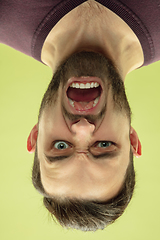 Image showing Inverted portrait of caucasian young man on yellow studio background