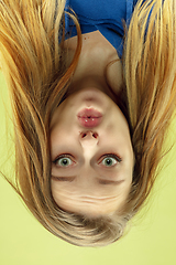 Image showing Inverted portrait of caucasian young woman on yellow studio background