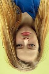 Image showing Inverted portrait of caucasian young woman on yellow studio background