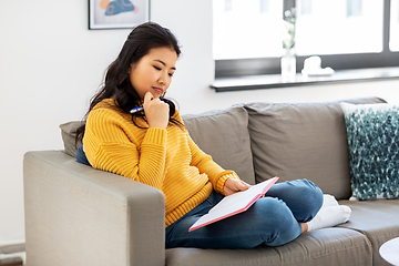 Image showing asian woman with diary sitting on sofa at home