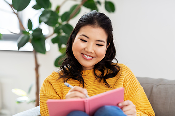 Image showing asian woman with diary sitting on sofa at home