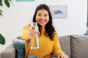 Image showing smiling asian young woman drinking water at home