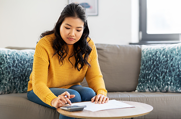 Image showing asian woman with papers and calculator at home