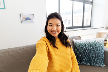 Image showing smiling asian young woman taking selfie at home