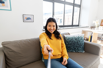 Image showing woman taking picture with selfie stick at home