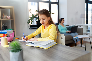 Image showing student girl with book writing to notebook at home