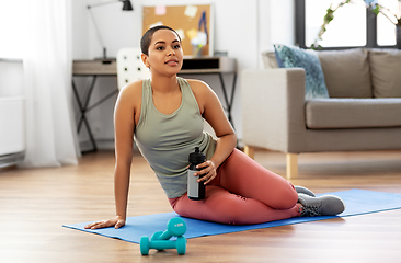 Image showing smiling woman with bottle and dumbbells at home