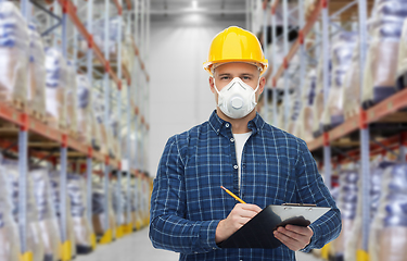 Image showing male worker in mask with clipboard at warehouse