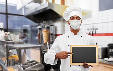 Image showing chef in face mask with chalkboard at kitchen