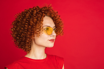 Image showing Caucasian woman\'s portrait isolated over red studio background with copyspace