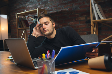 Image showing Young man working in modern office using devices and gadgets. Making reports, analitycs, routine processing tasks