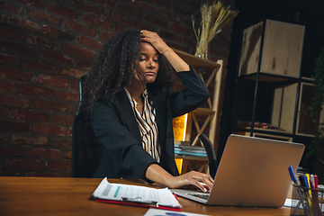 Image showing Young woman working in modern office using devices and gadgets. Making reports, analitycs, routine processing tasks